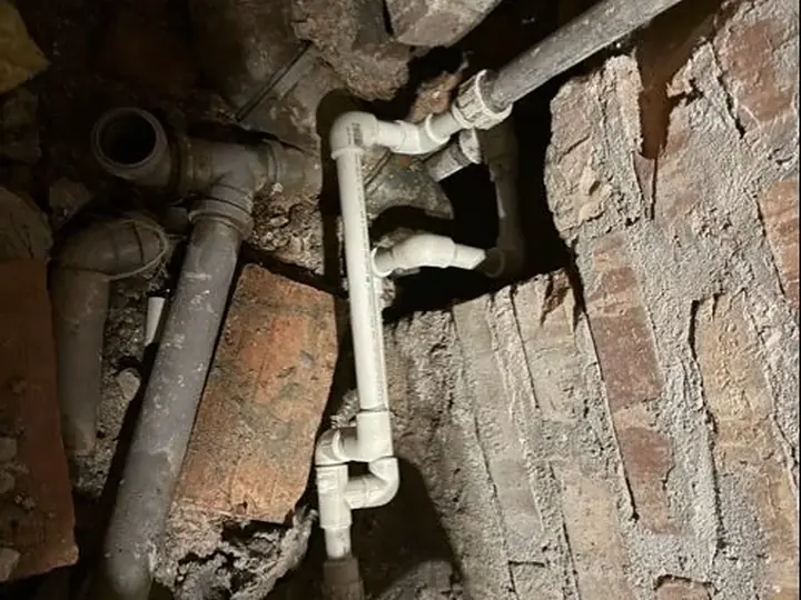 Stare rury żeliwne i PVC w rozkutym murze — DobryHydraulik Bydgoszcz